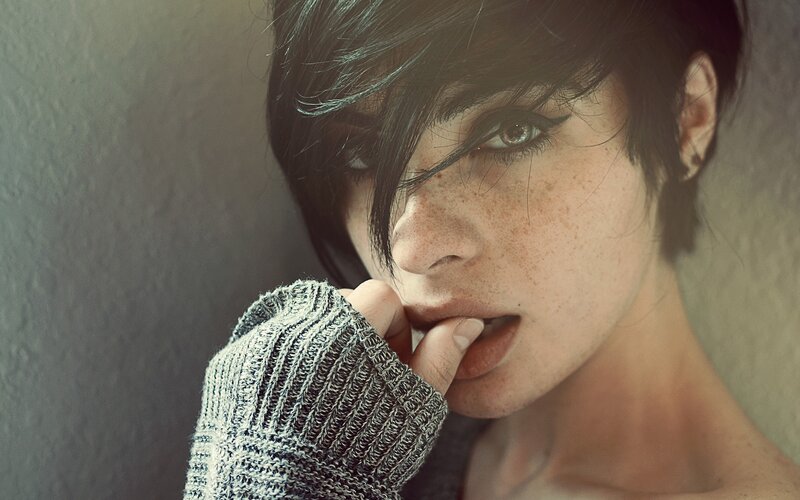 woman with freckles biting finger