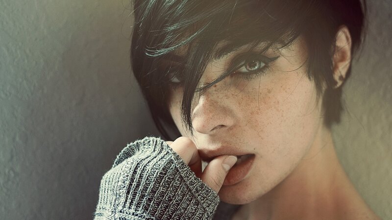 woman with freckles biting finger