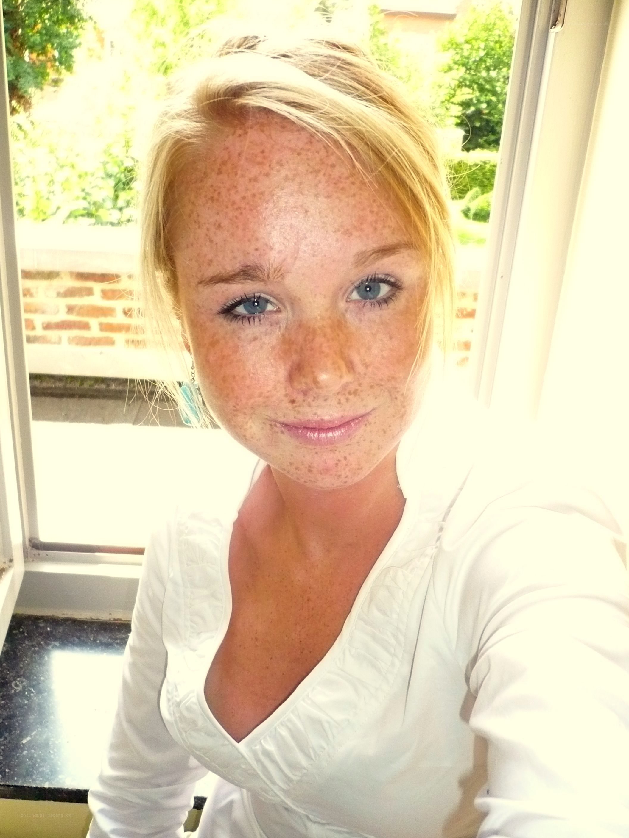 woman with freckles by window