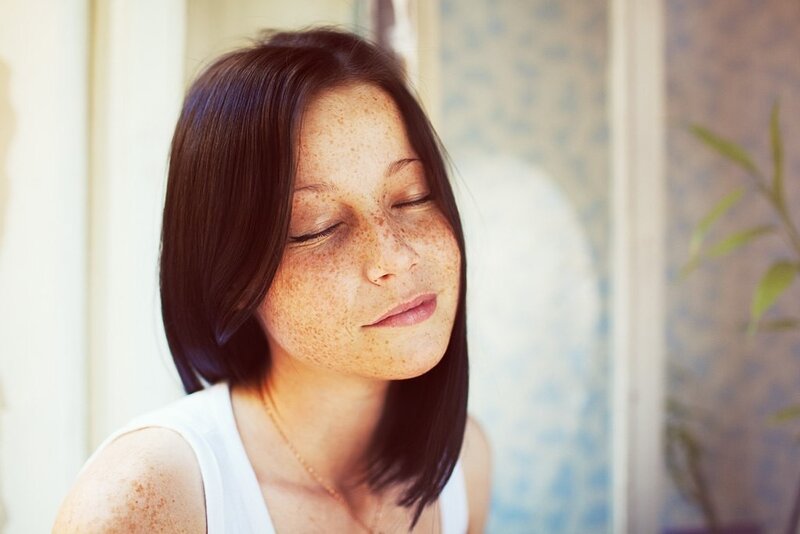 woman with freckles closing eyes