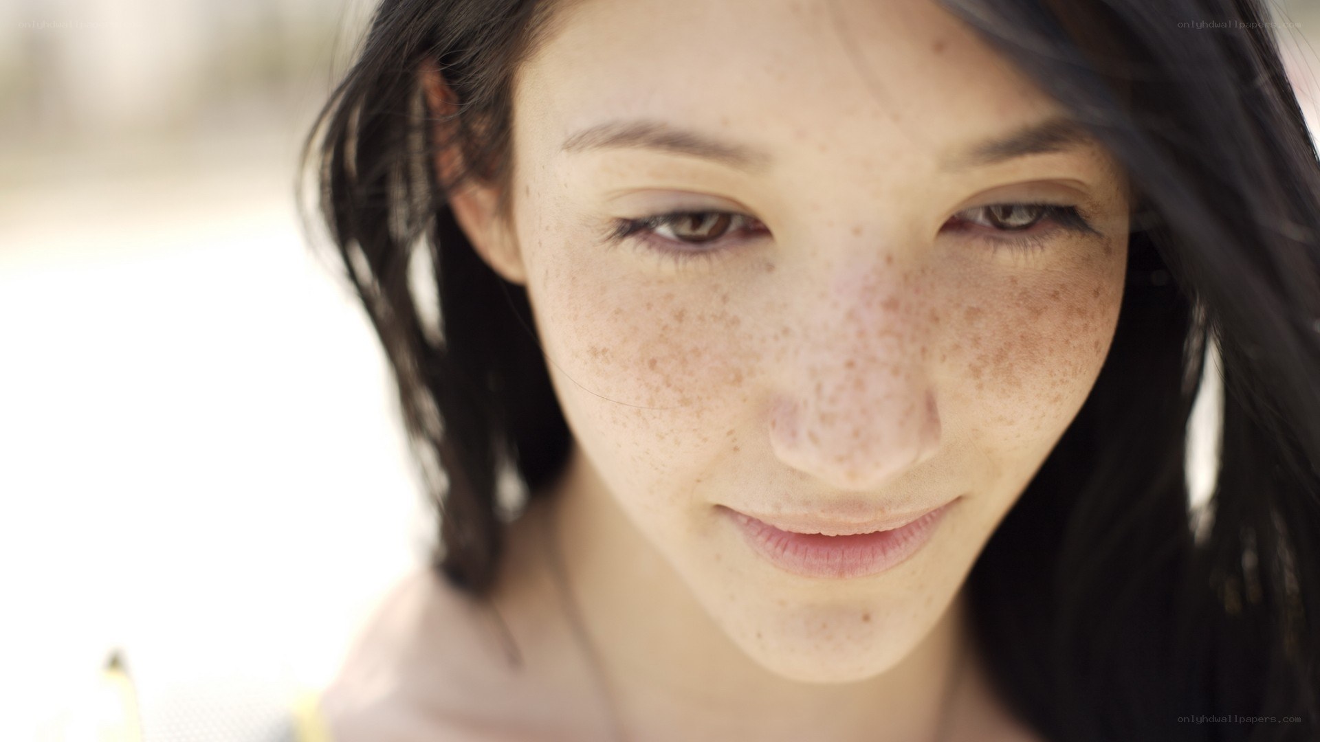 woman with freckles looking down