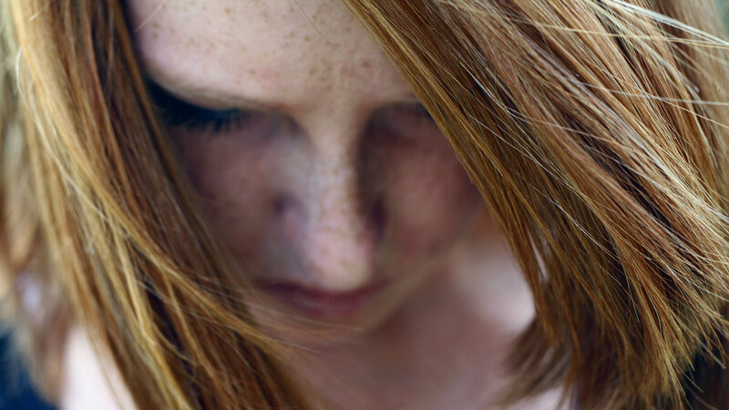 woman with freckles looking down