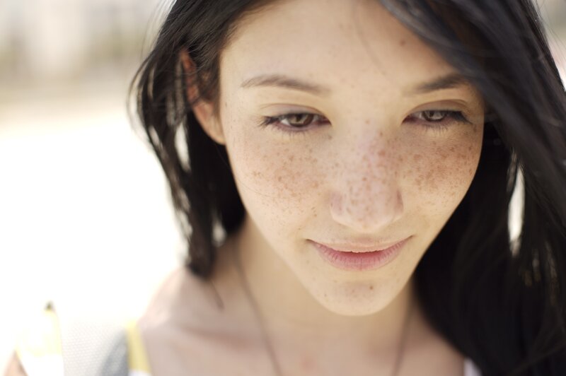 woman with freckles looking down