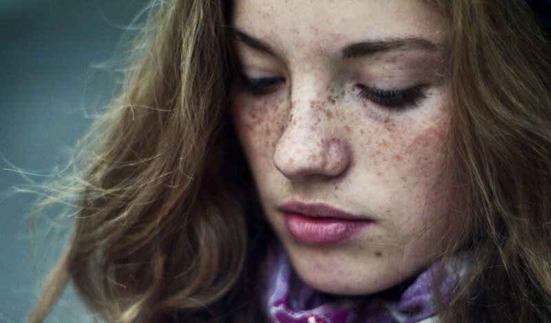 woman with freckles looking down