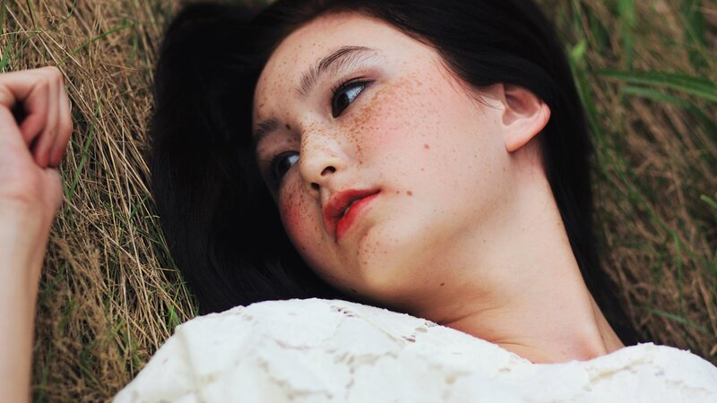woman with freckles lying in grass