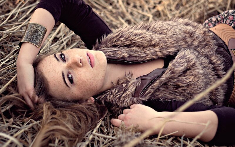 woman with freckles lying in hay
