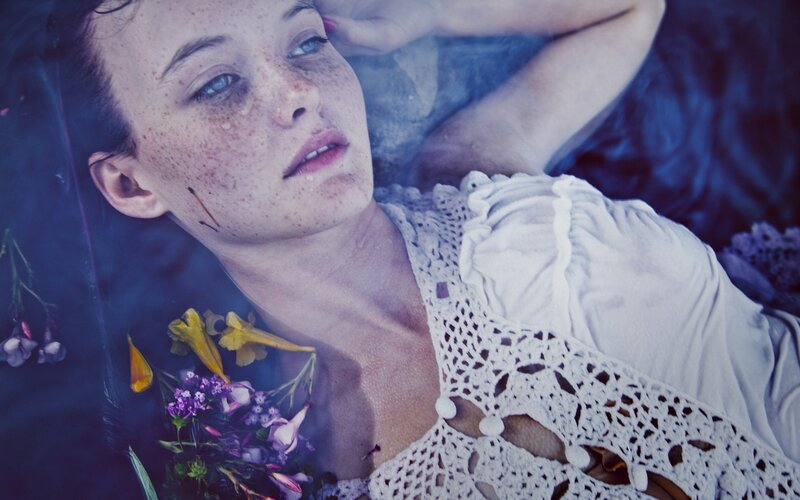 woman with freckles lying in water