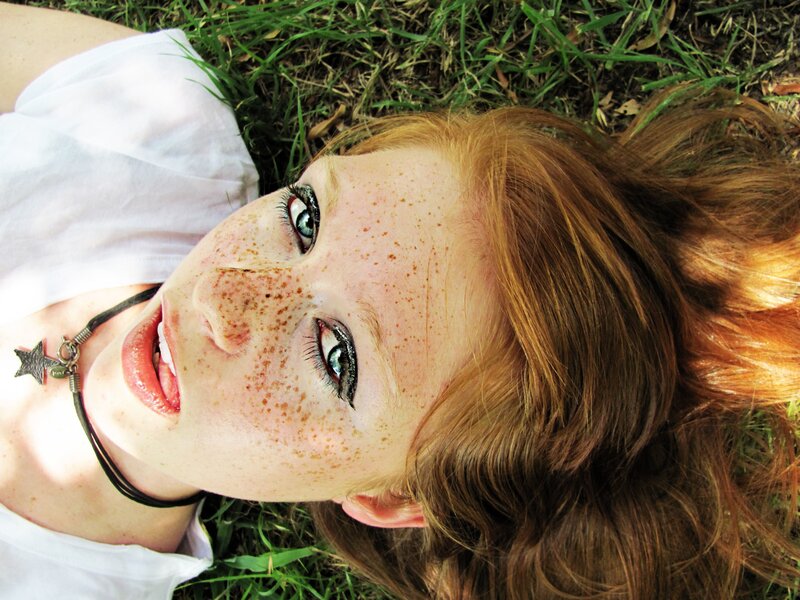 woman with freckles lying on grass