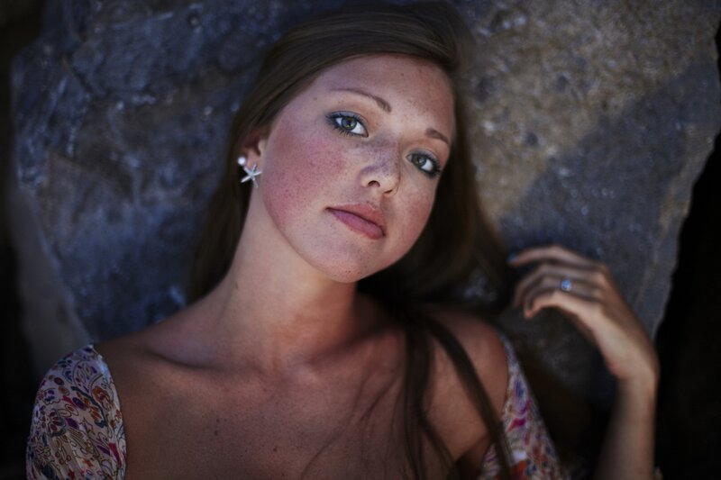 woman with freckles lying on rock