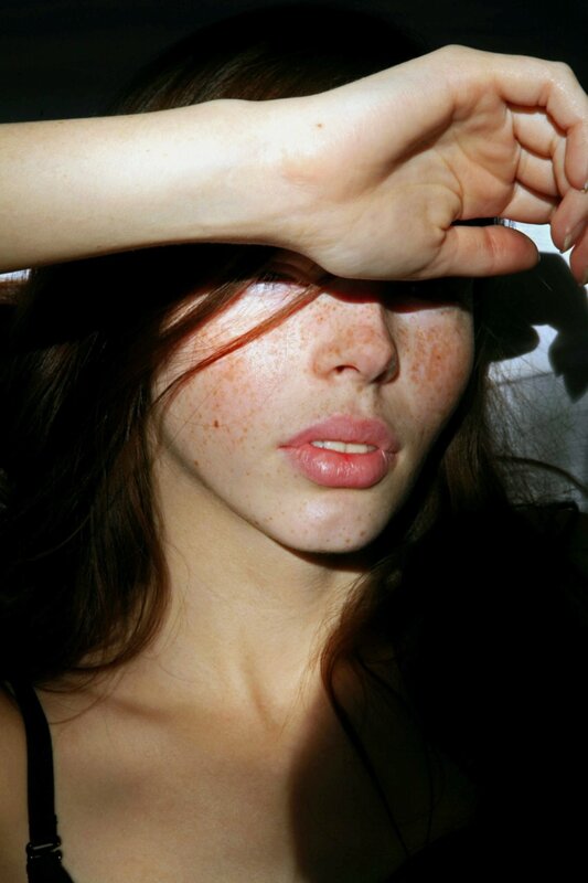 woman with freckles shading eyes