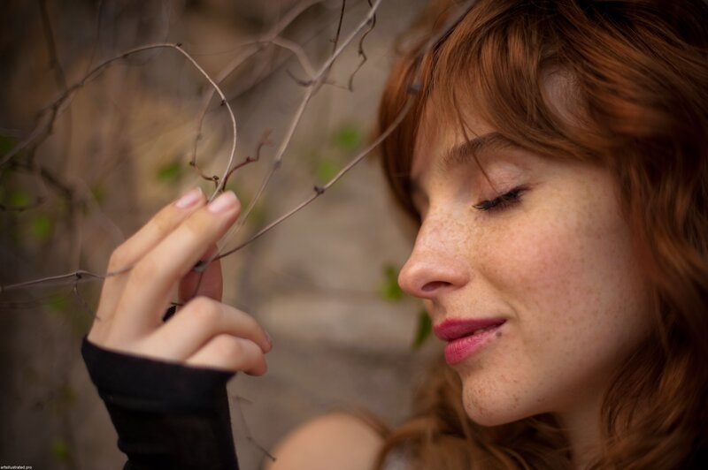 woman with freckles touching a vine