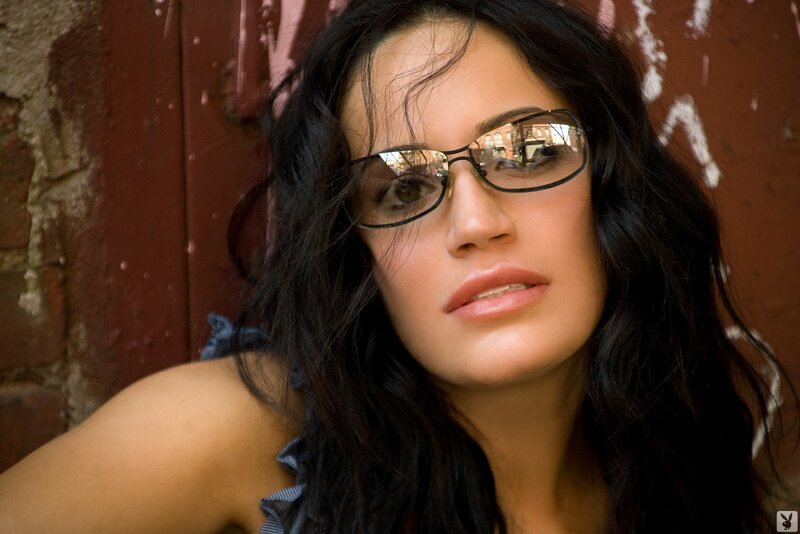 woman with glasses against brick wall