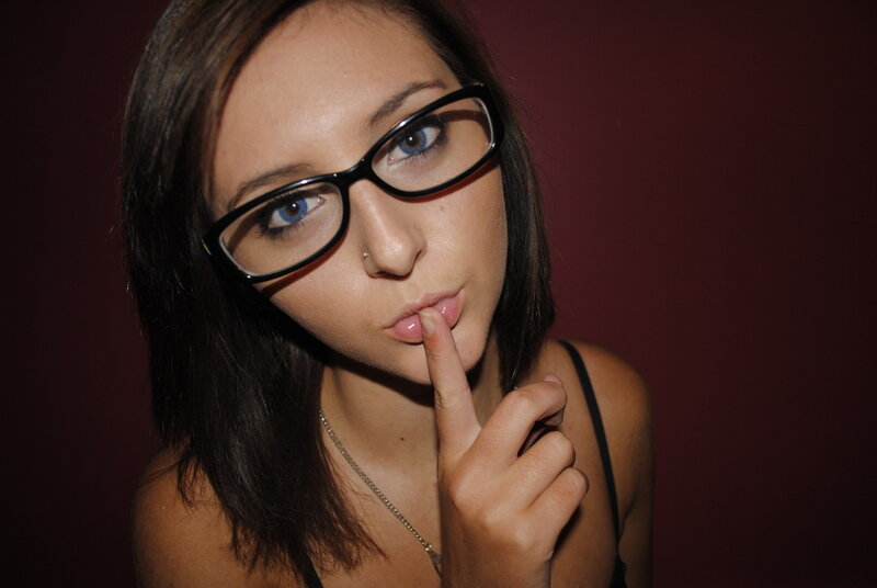 woman with glasses making a shushing gesture