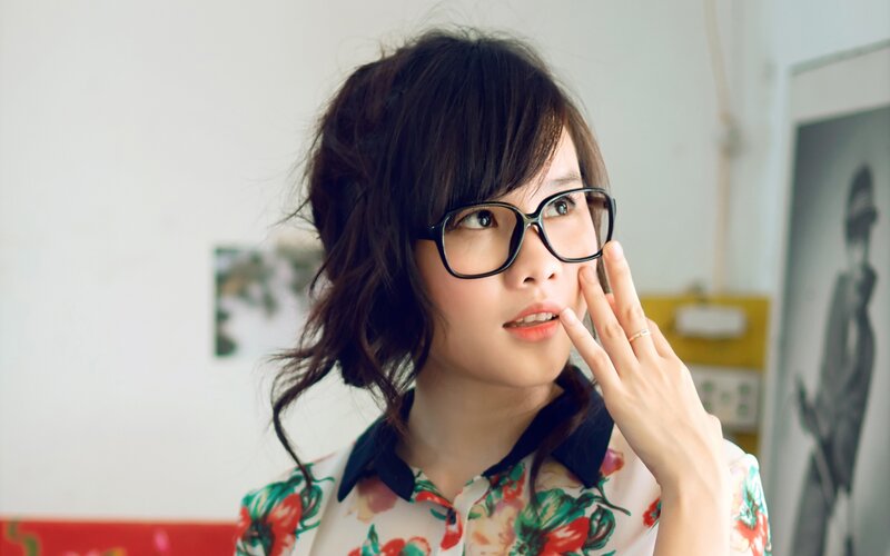 woman with glasses touching face