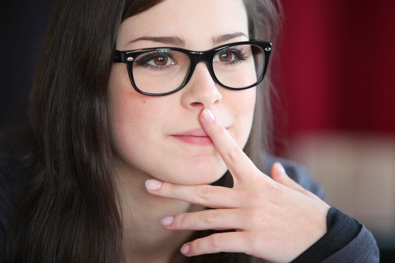 woman with glasses touching her face