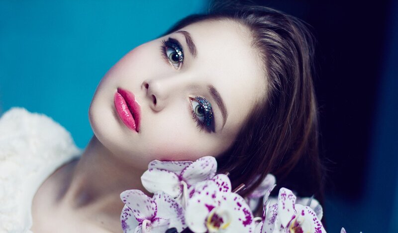 woman with glitter makeup and orchids