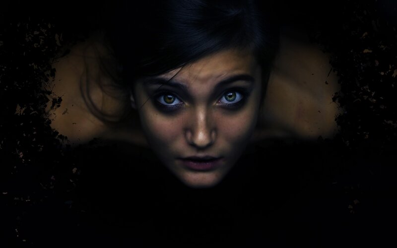woman with glowing eyes in darkness