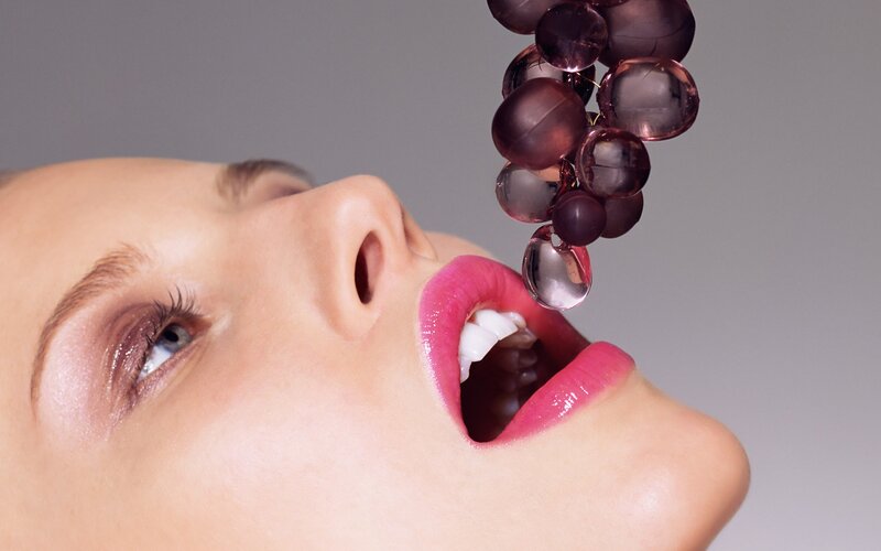 woman with grapes above mouth