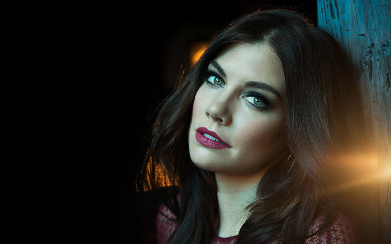 woman with green eyes leaning against wall