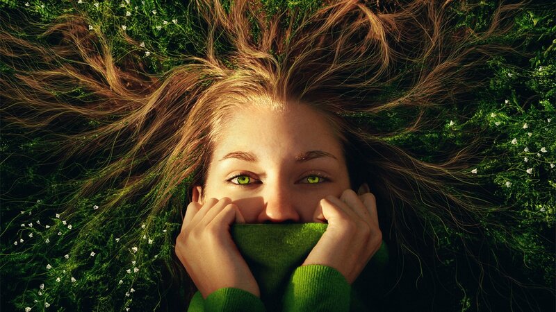 woman with green eyes lying in grass