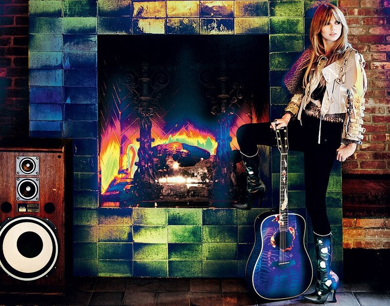 woman with guitar by fireplace