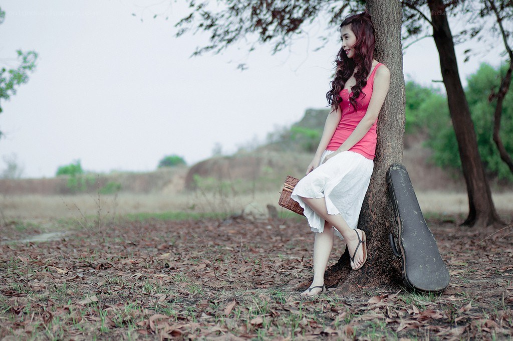 Woman with guitar case by tree