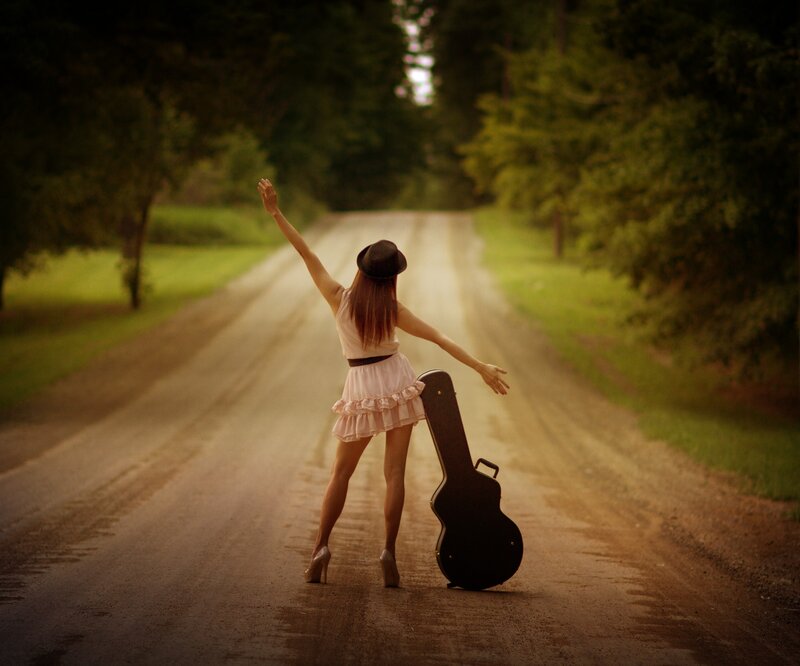 Woman with guitar case on road