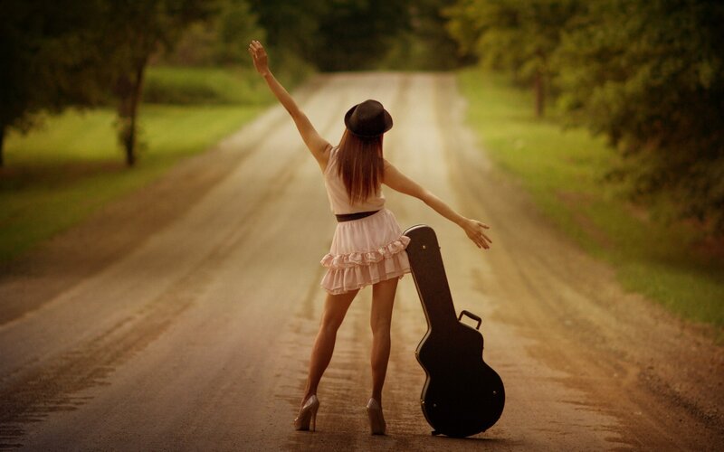 Woman with guitar case on road