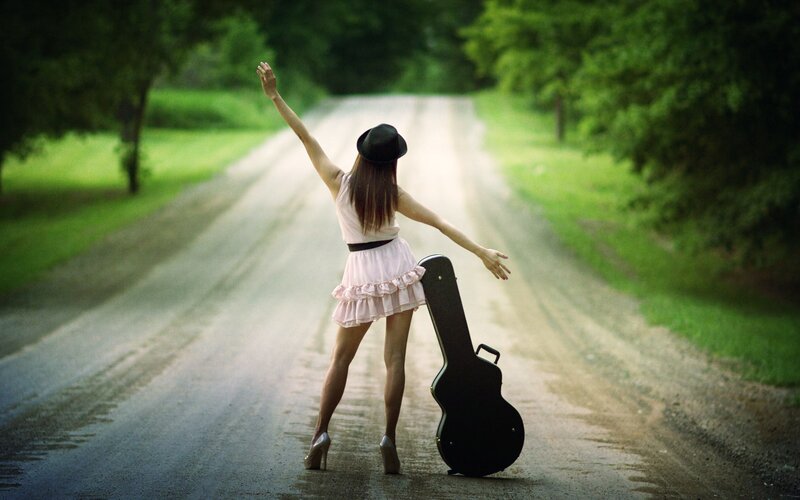 Woman with guitar case on road