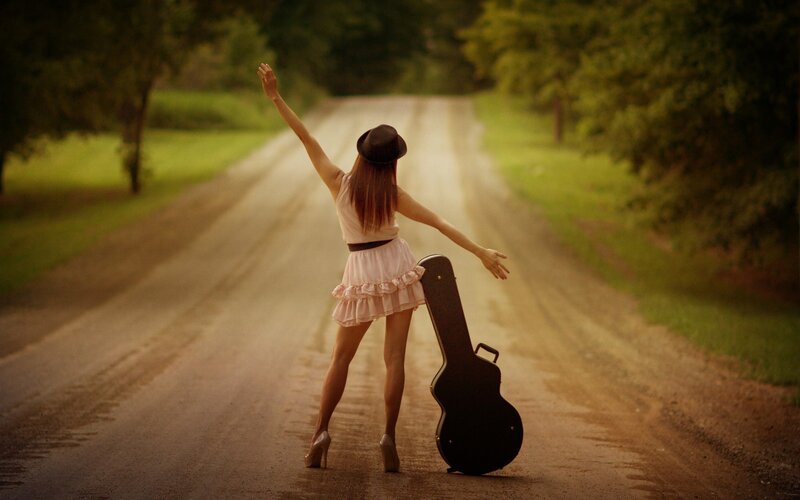 Woman with guitar case on road
