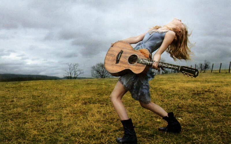 Woman with guitar in field