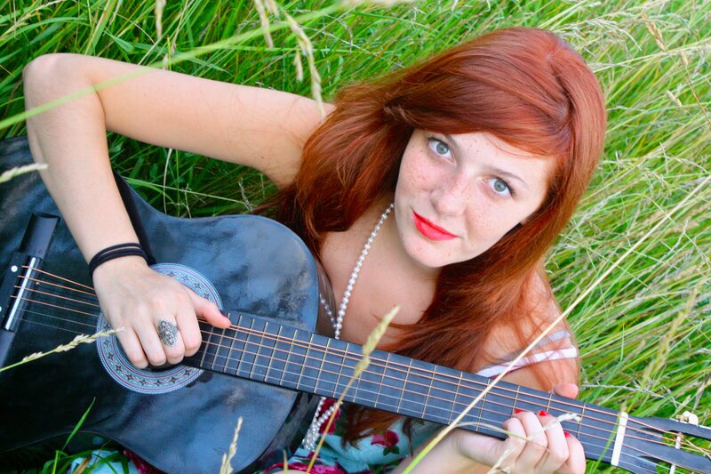 Woman with guitar in grass
