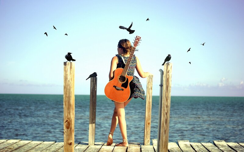 Woman with guitar on a pier