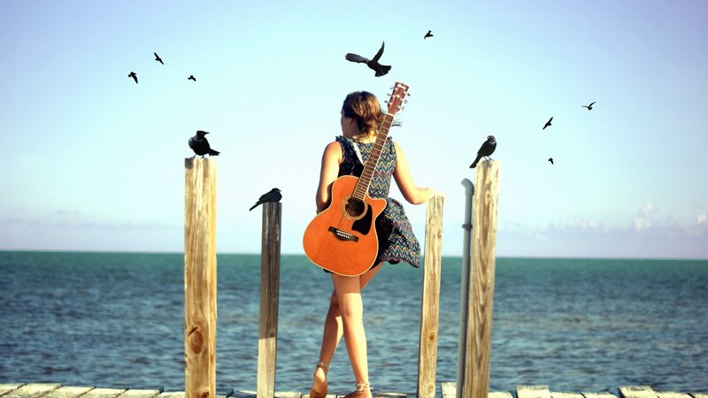 Woman with guitar on a pier