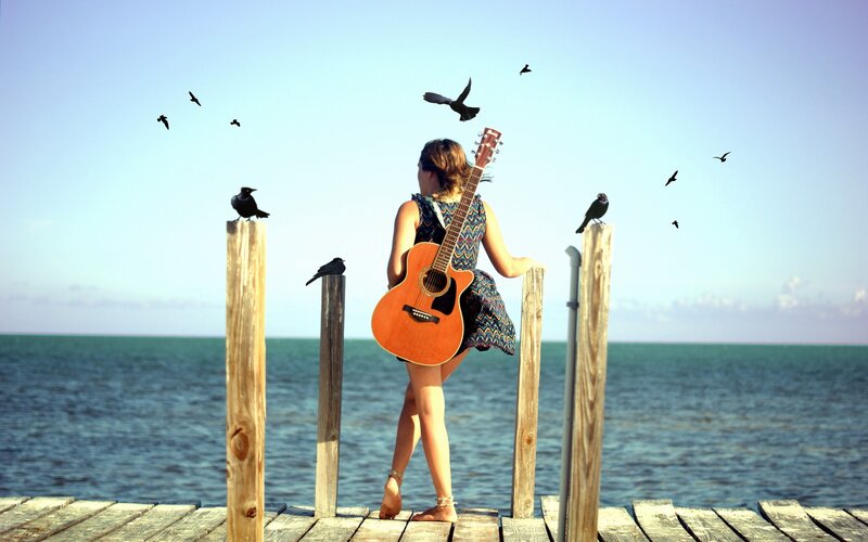 Woman with guitar on a pier