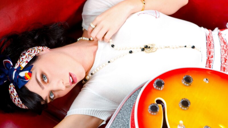 woman with guitar on red couch