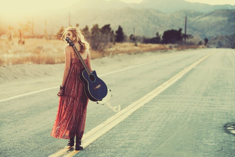 Woman with guitar on road