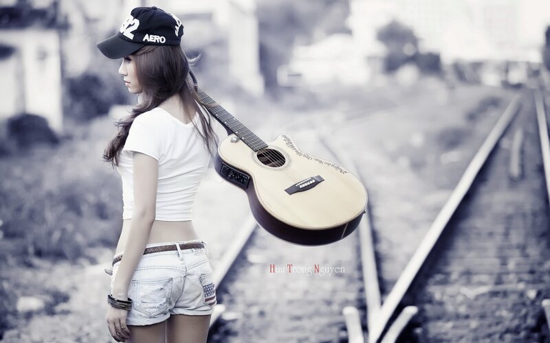 woman with guitar on train tracks