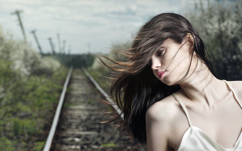 woman with hair blowing on train tracks