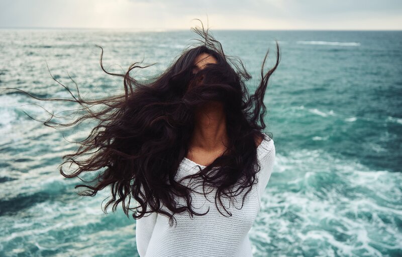 woman with hair in wind by sea