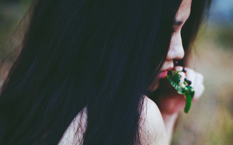 woman with long hair holding a leaf