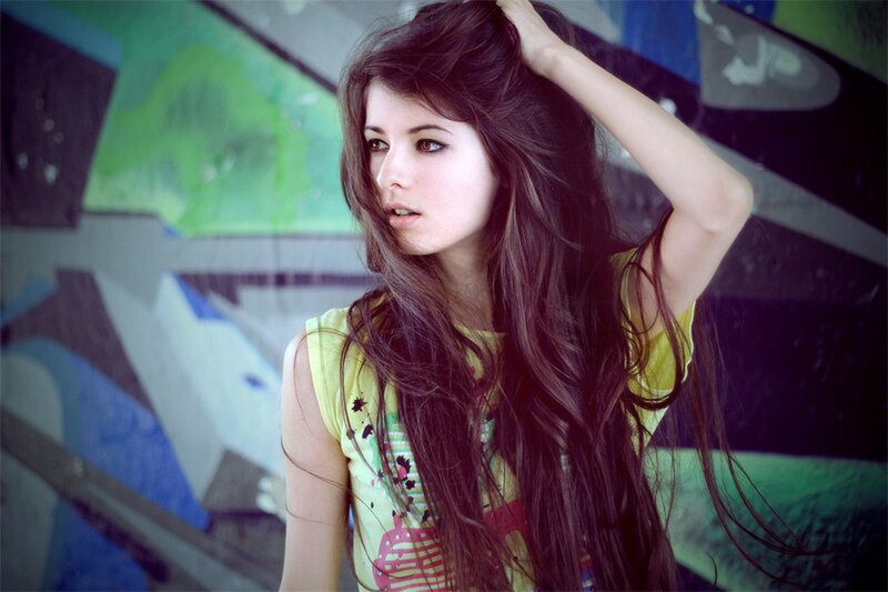 woman with long hair in front of graffiti
