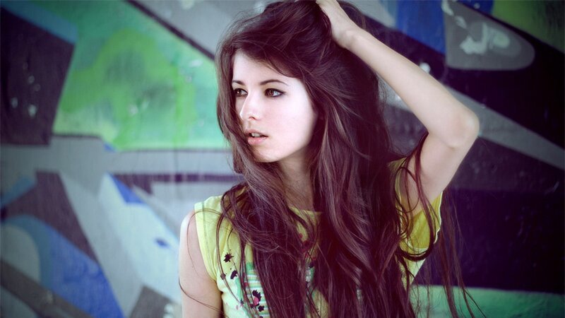 woman with long hair in front of graffiti