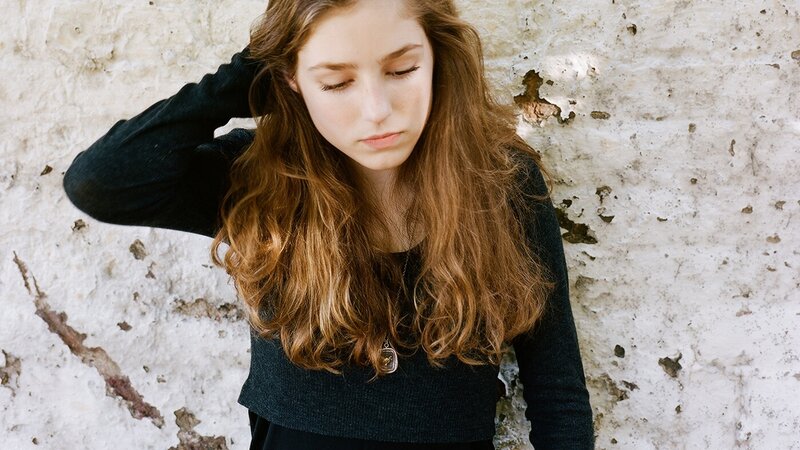 woman with long hair leaning against wall