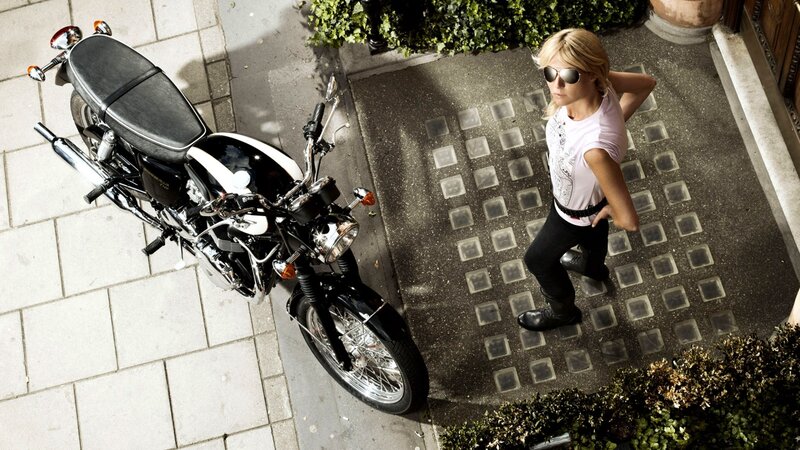woman with motorcycle on sidewalk