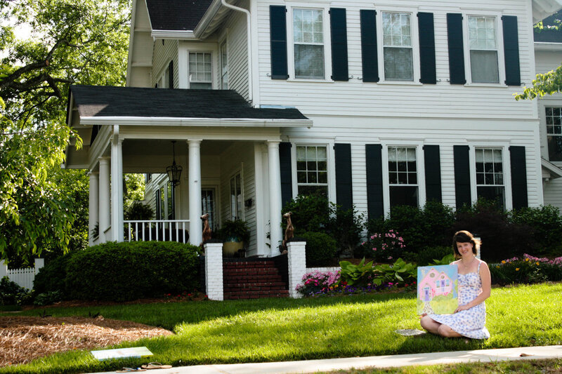Woman with painting in front of house