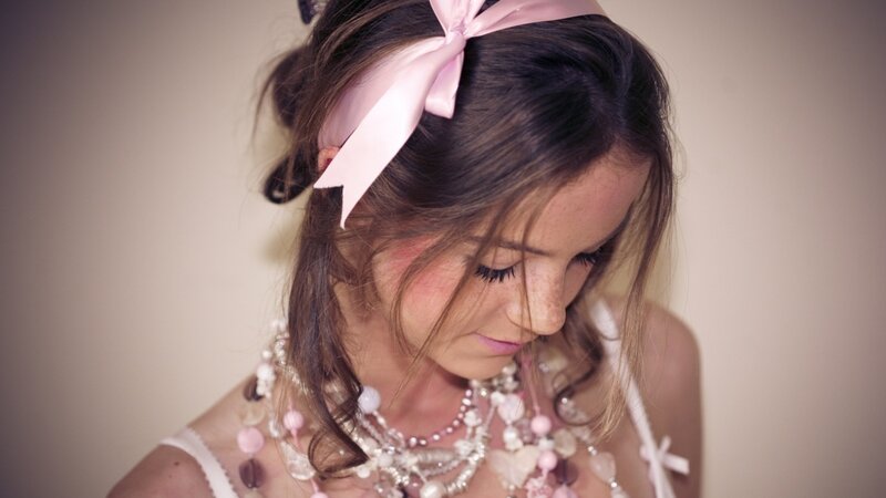 woman with pink bow and necklaces