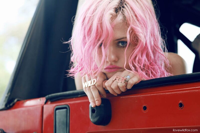 woman with pink hair in red car
