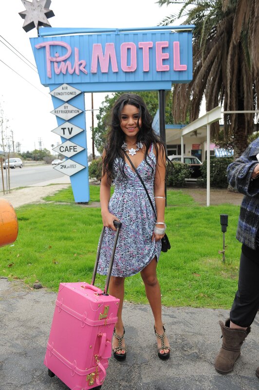 Woman with pink suitcase at motel