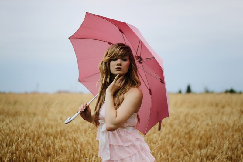Woman with pink umbrella in field